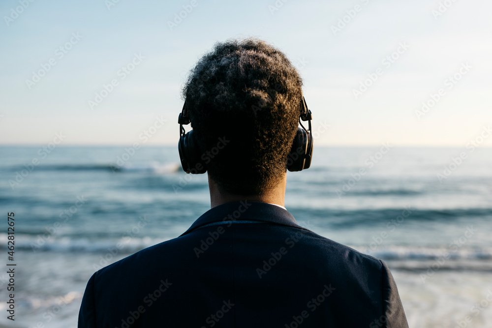 Afro man with headphones at beach
